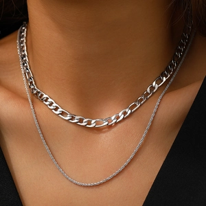Détail de la double chaîne argentée style cubain et torsadée sur le cou