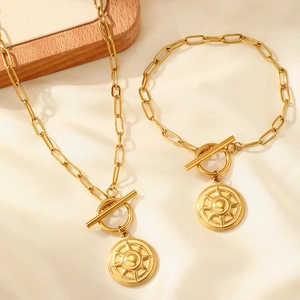 Detail of gold paperclip chain necklace and bracelet set with starburst toggle pendants
