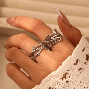 Detail of stacked silver thorn branch rings showing intricate wave lines and beads