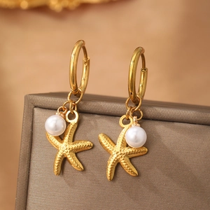 Gold stainless steel starfish earrings featuring hanging pearls on a luxury jewelry box