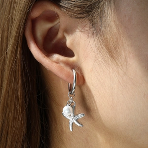 Detail of starfish earring with pearl on model's ear showing silver finish and texture