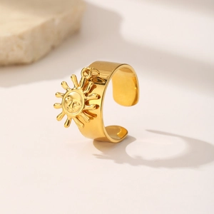 Detail of a wide gold stainless steel open ring with a sun face pendant and vintage finish