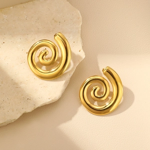 Detail of gold twisted spiral earrings on beige stone showing polished metal texture