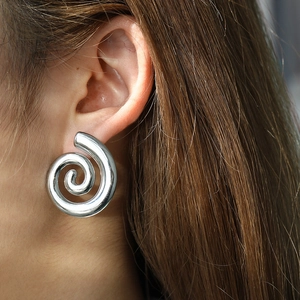 Detailed close-up of a silver polished spiral earring worn by a model in a modern style