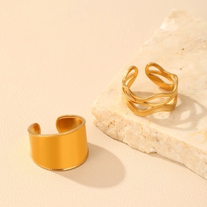 Detailed view of 18k gold double-layer textured and wave-pattern open rings on stone base