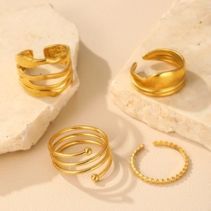 Detail of four gold irregular line stainless steel rings on a natural stone base