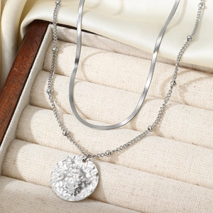 Detail view of silver double-layered chain necklace featuring a hammered metal circle pendant