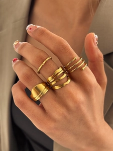 Detail view of a four-piece gold ring set featuring irregular wave and spiral designs