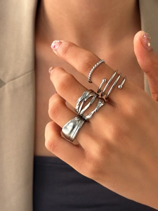 Close-up of four silver stainless steel rings with irregular textures on a female hand