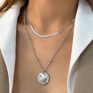Detail view of double-layer silver chain necklace with a hammered round metal pendant