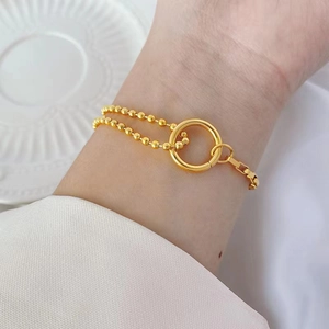 Elegant gold beaded chain bracelet with circle ring clasp worn on a woman's wrist