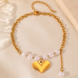 Elegant gold heart pendant bracelet with white freshwater pearls on silk background