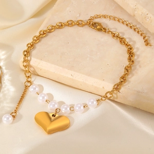 Elegant gold heart bracelet featuring white pearls and polished chain on satin background