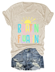 Flat lay of oat beige t-shirt with rainbow boating graphics and ripped blue denim shorts