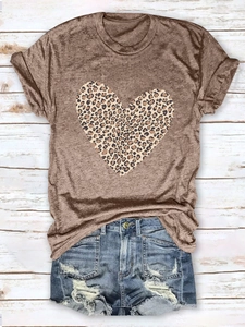 Flat lay of leopard heart print t-shirt and distressed denim shorts on wood background