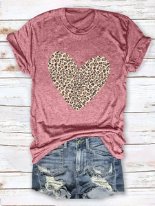 Flat lay of pink leopard heart print T-shirt paired with distressed denim shorts on wood