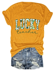 Flat lay of orange Lucky Teacher t-shirt with shamrock pattern and ripped denim shorts