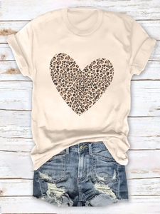 Flat lay of a beige t-shirt with leopard heart print and ripped denim shorts on wood