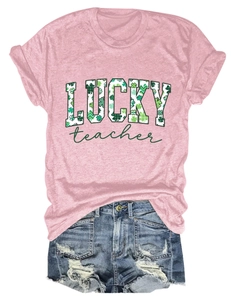 Detailed flat lay of pink Lucky Teacher T-shirt with shamrock pattern and denim shorts