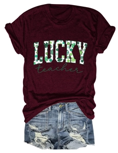 Flat lay of a red round neck T-shirt with LUCKY teacher clover print and denim shorts