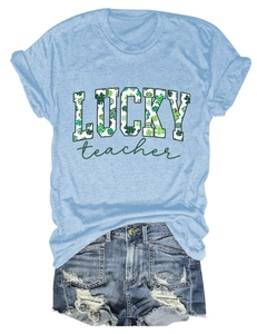 Flat lay of light blue Lucky Teacher T-shirt with St. Patrick's Day clover print and denim shorts