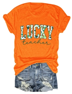 Flat lay of orange t-shirt featuring 'LUCKY teacher' print with green clover patterns