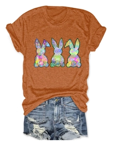 Detail of vibrant orange T-shirt featuring three colorful bunny silhouettes with artistic patterns