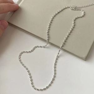 Detailed close-up of silver rice bead necklace with adjustable extension chain on book