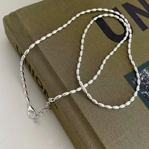 Silver olive bead necklace with adjustable lobster clasp on a green book background