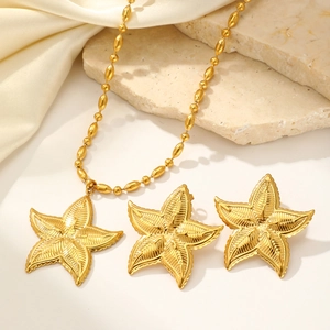 Elegant gold starfish necklace and earring set displayed on silk and natural stone