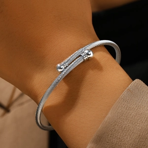 Brazalete ajustable de acero inoxidable plateado con diseño de cable y puntas de bola