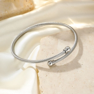 Brazalete de cable trenzado plateado con terminales de doble esfera sobre base de piedra