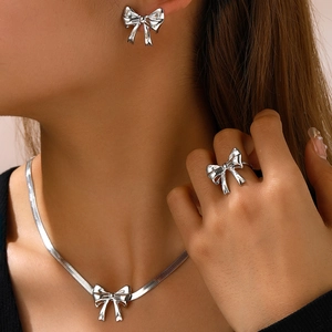 Silver bow jewelry set with snake chain necklace, ring and studs worn by a model