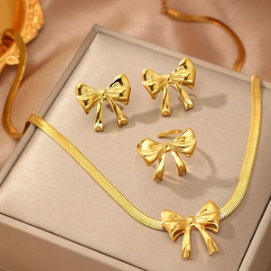 Elegant gold bow jewelry set with snake chain necklace, ring and earrings on display