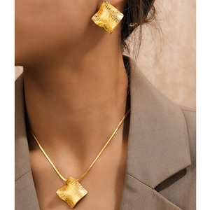 Goldenes Schmuckset mit quadratischer Textur aus Halskette und Ohrringen an einem Model