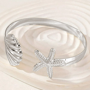 Silver ocean star and seashell bangle with textured metallic finish on wave background