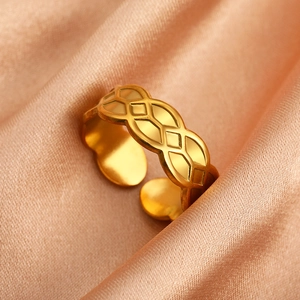 Nahaufnahme eines goldenen Rings mit geometrischem Muster auf Champagner-Satin