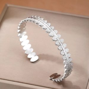 Silver geometric open bangle featuring a unique textured leaf pattern on a display box