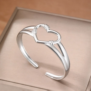 Bracciale rigido argento minimalista con design a cuore cavo e dettagli intrecciati