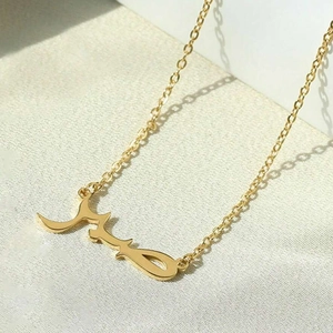 18K gold plated titanium necklace with Arabic Sabr calligraphy pendant on textile background