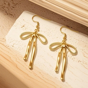 18K gold plated stainless steel bow ribbon drop earrings for women on stone display