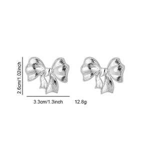 Boucles d'oreilles nœud argentées avec cœur et dimensions sur fond blanc épuré