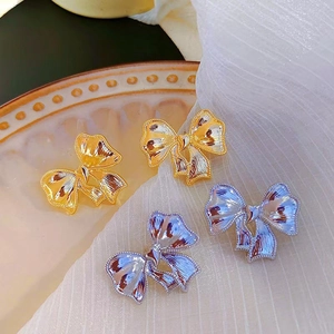 Boucles d'oreilles nœud en or et argent sur un plateau décoratif en céramique