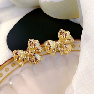 Boucles d'oreilles nœud doré avec texture radiale sur plateau en céramique vintage