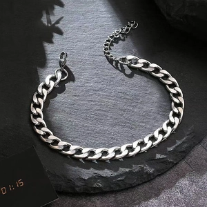 Polished silver stainless steel curb chain bracelet with lobster clasp on stone surface