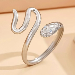 Adjustable snake-shaped stainless steel ring with crystal eyes on peach background
