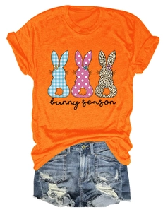 Mise à plat d'un t-shirt orange imprimé lapin avec un short en jean délavé