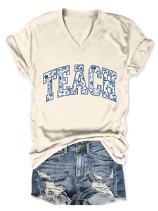 Dettaglio della t-shirt bianca con scollo a V, stampa TEACH e pantaloncini denim