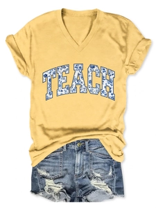 Dettaglio della t-shirt gialla con scollo a V, stampa TEACH e pantaloncini di denim