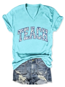 Dettaglio della maglietta scollo a V con scritte floreali TEACH e shorts